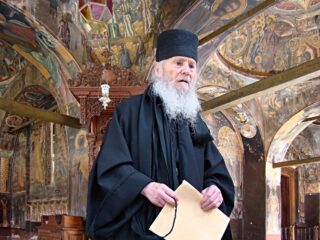 Een 90-jarige monnik geeft uitleg bij fresco’s met bijbelse taferelen in de kerk van klooster Kouloumousiou.