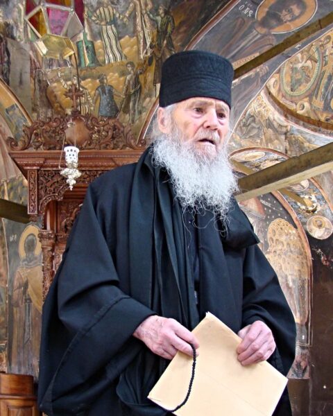 Een 90-jarige monnik geeft uitleg bij fresco’s met bijbelse taferelen in de kerk van klooster Kouloumousiou.