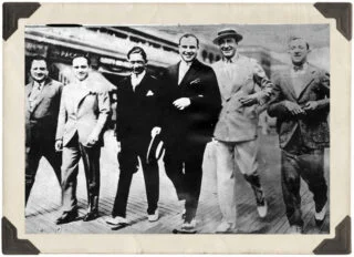 Al Capone, samen met Enoch Lewis ‘Nucky’ Johnson (vierde en vijfde van links) aan de wandel op de strandpromenade van Atlantic City, ofwel de ‘Boardwalk’