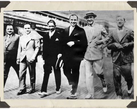 Al Capone, samen met Enoch Lewis ‘Nucky’ Johnson (vierde en vijfde van links) aan de wandel op de strandpromenade van Atlantic City, ofwel de ‘Boardwalk’