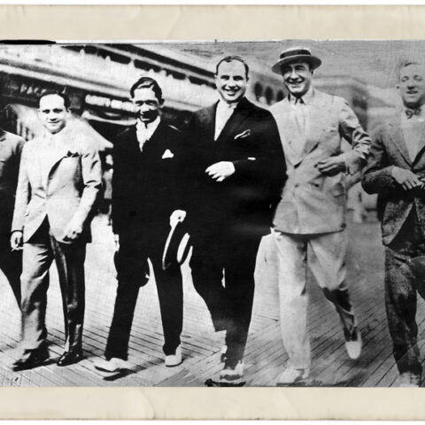 Al Capone, samen met Enoch Lewis ‘Nucky’ Johnson (vierde en vijfde van links) aan de wandel op de strandpromenade van Atlantic City, ofwel de ‘Boardwalk’