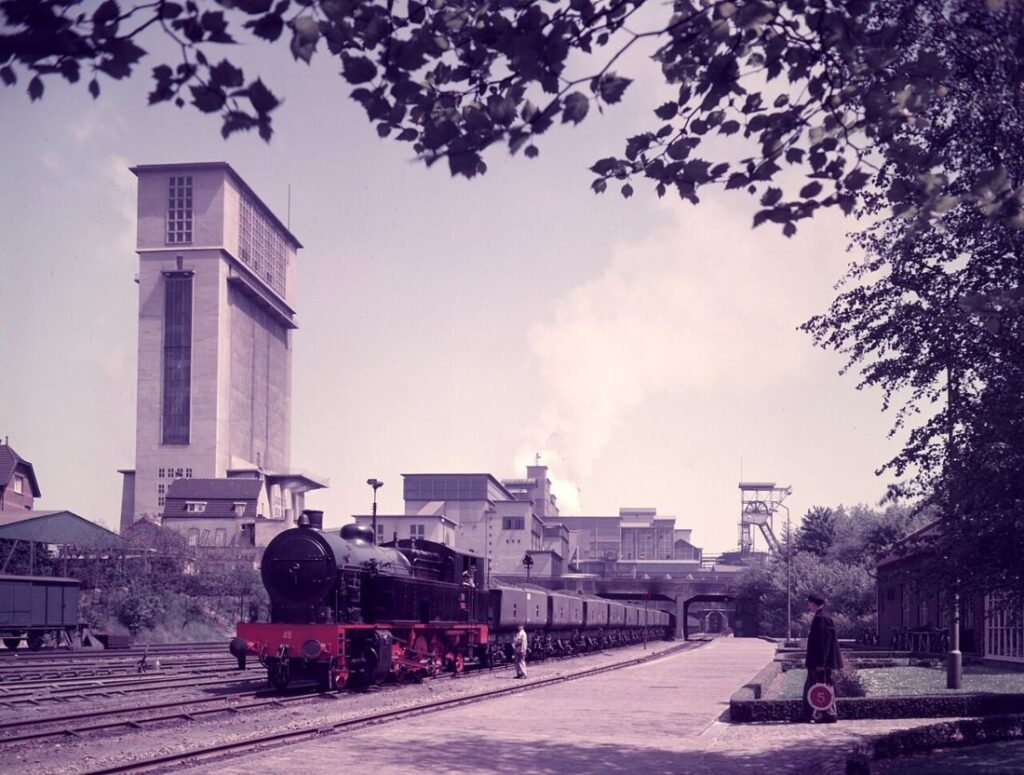 Een stoomlocomotief met kolenwagons op het spoorwegemplacement van de Staatsmijn Emma in Hoensbroek, mei 1955