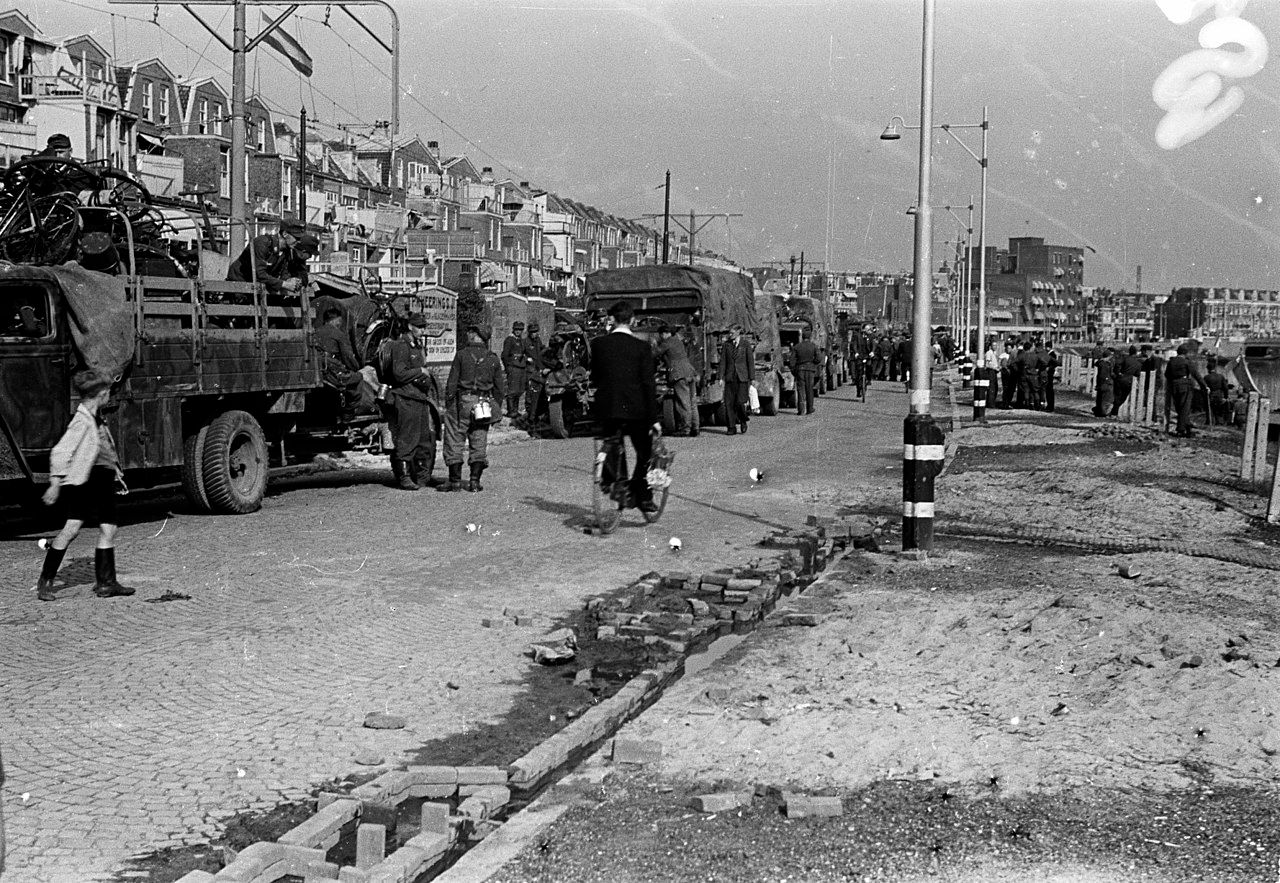 Duitse militairen staan na hun overgave op het punt te vertrekken, met vrachtauto's vol gevorderde spullen, waaronder fietsen.