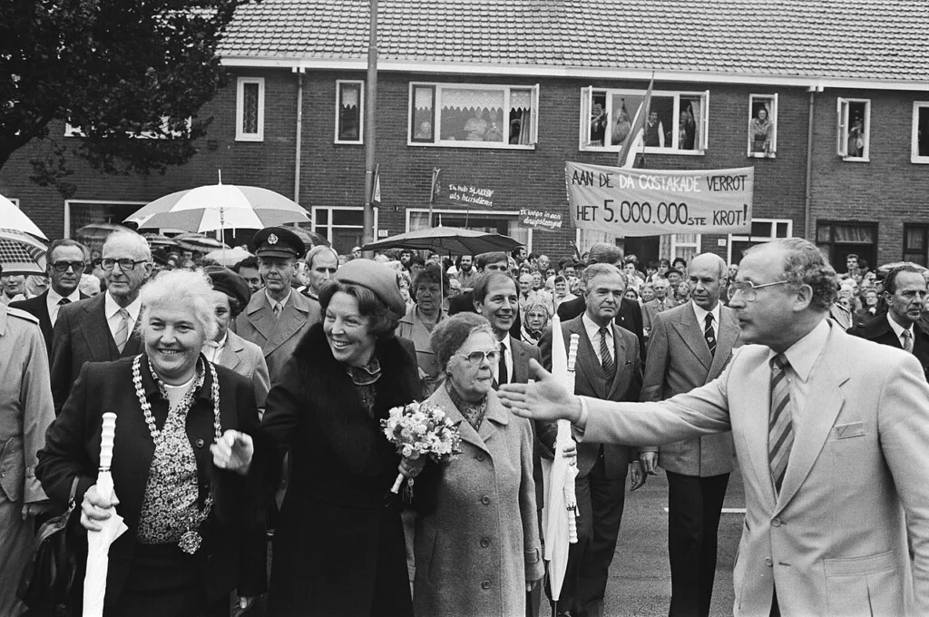 Koningin Beatrix tijdens haar bezoek aan Utrecht in 1982. Op de achtergrond is een protestspandoek te zien met de tekst 'Aan de Da Costakade verrot het 5.000.000ste krot!'