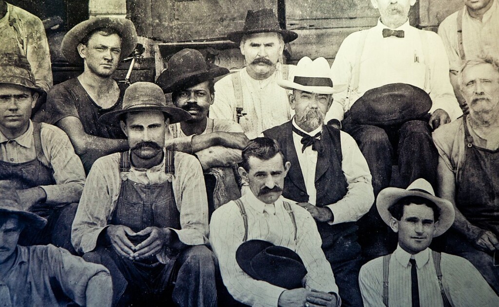 Foto uit 1904 van de het personeel van de distilleerderij van Jack Daniel, die zelf in het midden zit. Recht van hem zit George Green, de zoon van Nathan "Nearest" Green