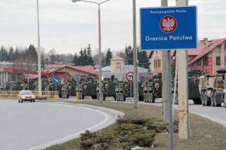NAVO-pantservoertuigen passeren de voormalige grensovergang Budzisko–Kalvarija op weg naar Litouwen