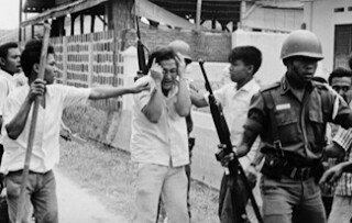 Een door burgers van communistische sympathieën beschuldigde student in Jakarta wordt afgevoerd door een militair. 