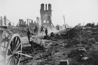 Verwoeste middeleeuwse lakenhalle en de belforttoren in Ieper tijdens de Eerste Wereldoorlog, met soldaten tussen het puin. circa 1916