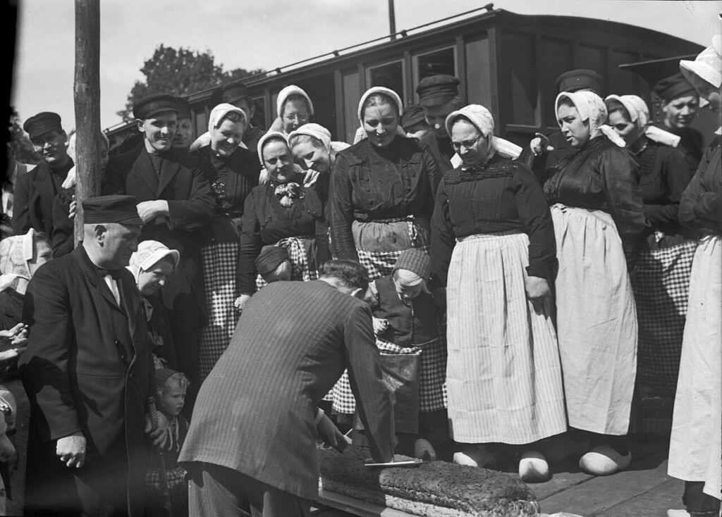 Het aansnijden van een krentenwegge tijdens een tentoonstelling in Enschede, 1951.